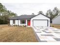 Newly built home with a red door and a geometric driveway at 13050 Ne 7Th Loop, Silver Springs, FL 34488