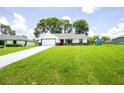 Wide view of a modern home with a spacious yard under a clear blue sky and puffy white clouds at 13050 Ne 7Th Loop, Silver Springs, FL 34488