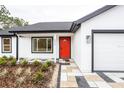 Modern white house with red door, gray and white paved walkway, and landscaping at 13050 Ne 7Th Loop, Silver Springs, FL 34488