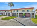 Townhouse exterior with multiple car garage, red roof, and green space with a healthy palm tree at 14 Ocean Palm Villa S # 14, Flagler Beach, FL 32136