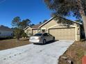 Tan one-story house with attached garage and driveway, surrounded by trees and landscaping at 1067 Dudley Dr, Kissimmee, FL 34758