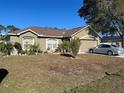 Tan one-story house with attached garage and driveway, surrounded by trees and landscaping at 1067 Dudley Dr, Kissimmee, FL 34758