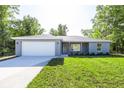 Charming single-story home featuring a two-car garage and a well-manicured lawn, nestled among mature trees at 8873 Sw 139Th Place Rd, Ocala, FL 34473