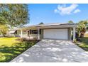 House exterior featuring a light green facade, attached garage, and a well-maintained lawn at 11436 Sw 84Th Court Rd, Ocala, FL 34481