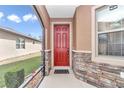 Inviting front porch with a red door, stone accents, and screened enclosure at 9664 Sw 76Th Lane Rd, Ocala, FL 34481