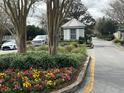 A small, quaint guard house stands amid colorful flowers and lush greenery at the neighborhood's entrance at 16862 Se 80 Bellavista Cir, The Villages, FL 32162