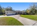 Single-story home with a well-manicured lawn and circular driveway leading to a three-car garage at 12880 Sw 66Th St, Ocala, FL 34481