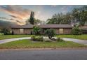 Charming brick home with circular drive and mature landscaping at sunset at 906 Crestview Dr, Auburndale, FL 33823