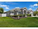 Charming gray home featuring a well-manicured lawn, lush landscaping, and a two-car garage at 14867 Bonnybridge Dr, Orlando, FL 32826