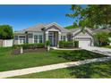 Charming gray home featuring a well-manicured lawn, lush landscaping, and a two-car garage at 14867 Bonnybridge Dr, Orlando, FL 32826