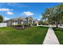 Charming gray home featuring a well-manicured lawn, lush landscaping, and a two-car garage at 14867 Bonnybridge Dr, Orlando, FL 32826