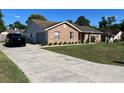 Lovely brick home featuring an attached garage, long driveway, and lush green lawn at 3295 Se 56Th Ave, Ocala, FL 34480
