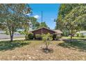 A wide front yard view showcasing a home with mature trees and neatly trimmed bushes at 8082 Sw 103Rd Ln, Ocala, FL 34481