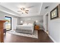 Cozy main bedroom with neutral tones, tray ceiling, wood floors, and natural light from the glass paneled door at 9945 Sw 55Th Avenue Rd, Ocala, FL 34476