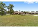 Expansive front lawn leading to a charming single-story home with mature landscaping and a red front door at 10458 Sw 52Nd Ct, Ocala, FL 34476