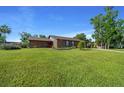 Well-maintained lawn and mature trees complement this lovely single-story brick house with a red front door at 2030 Se 32Nd Ln, Ocala, FL 34471