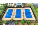 Aerial view of three well-maintained blue tennis courts enclosed by a black fence at 5237 Nw 48Th Pl, Ocala, FL 34482