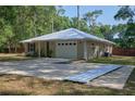 View of the home's exterior showcasing the long driveway, white metal roof, and landscaping around the front entryway at 3005 Se 156Th Place Rd, Summerfield, FL 34491