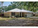 A well-maintained single-Gathering home with a white metal roof, beige exterior, and a nicely landscaped front yard at 3005 Se 156Th Place Rd, Summerfield, FL 34491