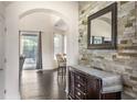 Elegant foyer featuring a decorative stone wall and dark wood floors, leading to a view of the outdoor pool area at 1157 Hollow Pine Dr, Oviedo, FL 32765
