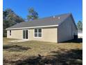 Rear exterior view of home, showcasing a sliding glass door and ample green space at 8881 Sw 138Th Ln, Ocala, FL 34473