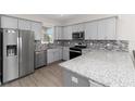 Modern kitchen with stainless steel appliances, granite countertops, gray cabinets, and mosaic tile backsplash at 8925 Sw 76Th St, Ocala, FL 34481