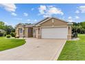 Stylish home showcasing a spacious driveway, pristine lawn, and an attached two-car garage at 1044 Sw 159Th St, Ocala, FL 34473