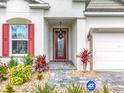 Welcoming front porch with a decorative front door, lovely landscaping, and an ADT security sign at 6612 Tempo Way, Mascotte, FL 34753