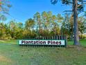 Entrance to Plantation Pines with sign surrounded by beautiful green landscaping, nature, and trees at 3682 Jack Pine Ln, Ormond Beach, FL 32174