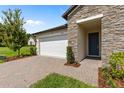 Close-up view of the home's exterior, showcasing the stone facade, two-car garage, and brick driveway at 3940 Se 5Th Ave, Ocala, FL 34480
