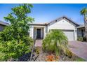 Inviting home featuring a manicured lawn, lush landscaping, brick driveway, and a welcoming front entrance at 1192 Via Galuppi St, Kissimmee, FL 34759