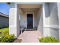 Welcoming front porch with a dark-colored front door, brick flooring, and a seating area at 1192 Via Galuppi St, Kissimmee, FL 34759