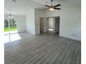 Open-concept living area with wood-look floors, neutral walls, ceiling fan, and sliding glass doors at 15433 Sw 47Th Avenue Rd, Ocala, FL 34473