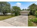 Driveway with a spacious two-car garage, set amidst a green yard and mature trees under a bright sky at 9879 Sw 38Th Ave, Ocala, FL 34476