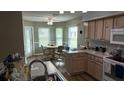 Eat-in kitchen with wood cabinets, stainless steel appliances, and a cozy breakfast nook by the windows at 32932 Crooked Oaks Ln, Leesburg, FL 34748
