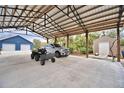 Large carport with ample space for vehicles, ATVs, and other equipment with a building and shed nearby at 112 Reedy Creek Dr, Frostproof, FL 33843