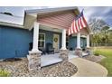 Inviting home featuring a covered front porch, stone accents, and charming curb appeal with an American flag at 112 Reedy Creek Dr, Frostproof, FL 33843