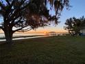 Picturesque waterfront property featuring a tranquil lake, dock, and moss-draped trees at sunset at 1301 S Lake Reedy Blvd, Frostproof, FL 33843