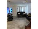 Cozy living room featuring tile floors, black leather couches, tv, and a ceiling fan at 1402 Thousand Roses Dr. W. # 1402, Lake Wales, FL 33853
