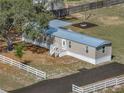 Aerial view of home with metal roof, covered porch and white fence-lined driveway at 2391 Buck Board Trl, Lake Wales, FL 33898