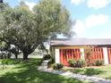 Charming exterior view showcasing a well-manicured lawn, mature trees, and a paved walkway at 1077 Medinah Way, Winter Haven, FL 33884