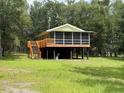 Elevated home with a screened-in porch, complemented by a lush green lawn and natural landscape at 1885 Pfundstein Rd, Babson Park, FL 33827