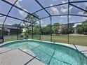 Tranquil screened-in pool with clear blue water, complemented by outdoor seating and serene surroundings at 2692 Hemingway Ave, Haines City, FL 33844