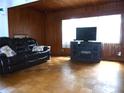 Comfortable living room with wood paneled walls, large window, and laminate wood floor at 302 S Palm Ave, Frostproof, FL 33843