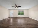 Bright living room featuring wood floors, a ceiling fan, a front door, and a large window with a pleasant view at 509 Mountain Dr, Babson Park, FL 33827