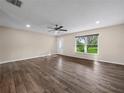 Bright and spacious living room featuring wood floors, a ceiling fan, and a large window with a pleasant view at 509 Mountain Dr, Babson Park, FL 33827