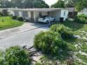 Lush front yard with flowering bushes leads to a covered carport of this single-story home at 7 Lamplight Ln, Winter Haven, FL 33884