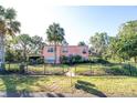 Charming two-story home with a manicured lawn, mature palm trees, and a black metal fence at 7254 Wisteria Ln, Lake Wales, FL 33898