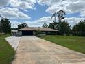 Well-maintained single-story home with a long driveway and mature landscaping at 7591 Limonia Dr, Indian Lake Estates, FL 33855