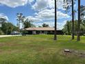 Single-story home with a well-manicured lawn and mature trees, offering a serene setting at 7591 Limonia Dr, Indian Lake Estates, FL 33855